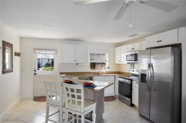 kitchen featuring white cabinetry, sink, light stone counters, light tile patterned floors, and appliances with stainless steel finishes