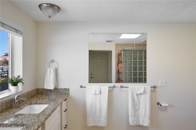 bathroom featuring a textured ceiling, vanity, and curtained shower