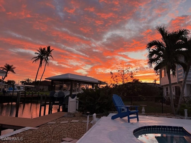 patio terrace at dusk featuring a gazebo and a water view