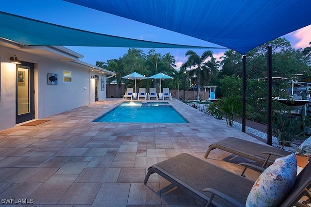 pool at dusk featuring a patio area