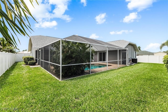 rear view of property featuring a lawn, a lanai, central air condition unit, and a fenced in pool