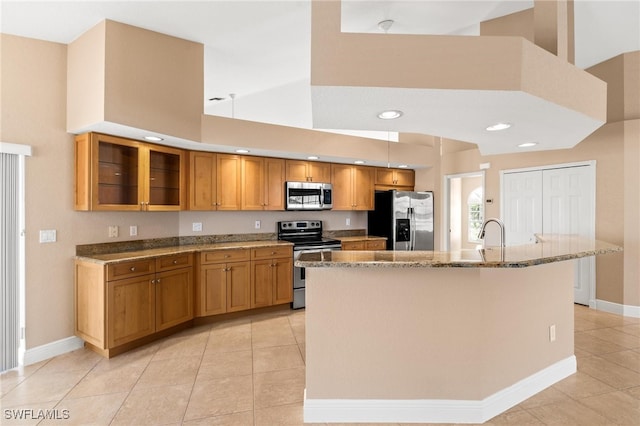 kitchen featuring a center island with sink, a towering ceiling, light tile patterned floors, and appliances with stainless steel finishes