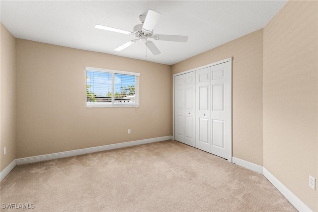 unfurnished bedroom featuring ceiling fan, light colored carpet, and a closet