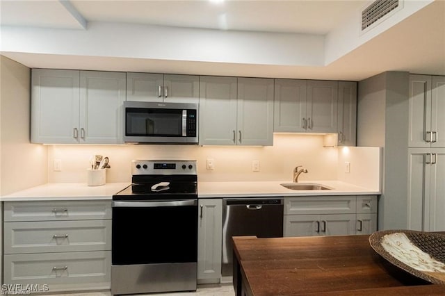 kitchen with gray cabinets, sink, and stainless steel appliances