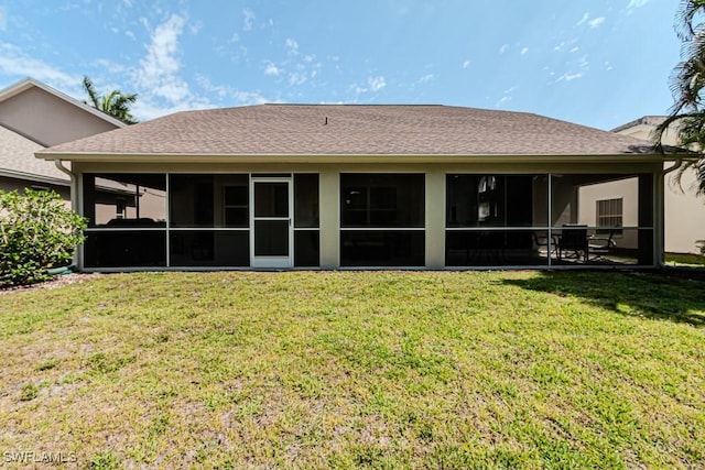 rear view of property featuring a shingled roof, a sunroom, and a lawn