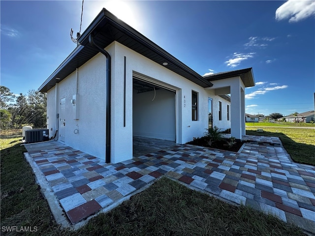 view of side of property featuring a yard, a patio, and central AC unit