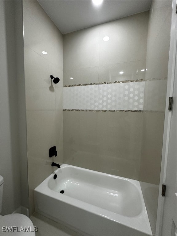 bathroom featuring tiled shower / bath combo and toilet