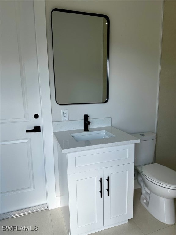 bathroom featuring tile patterned flooring, vanity, and toilet