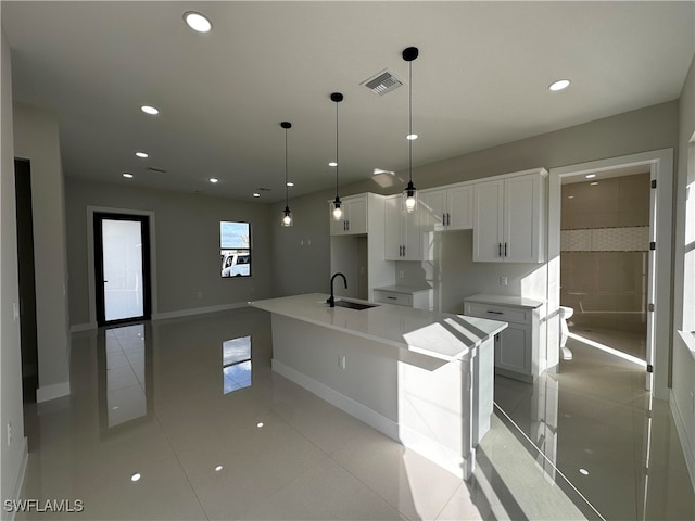 kitchen featuring white cabinetry, a center island with sink, decorative light fixtures, and sink