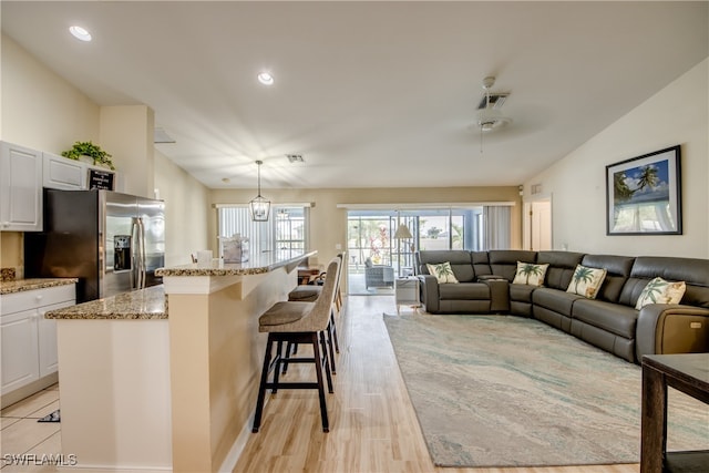 interior space with ceiling fan with notable chandelier, light wood-type flooring, and lofted ceiling