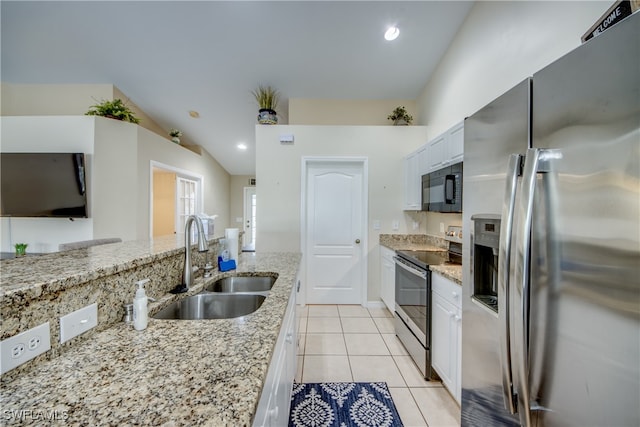 kitchen featuring light stone countertops, stainless steel appliances, vaulted ceiling, sink, and white cabinetry