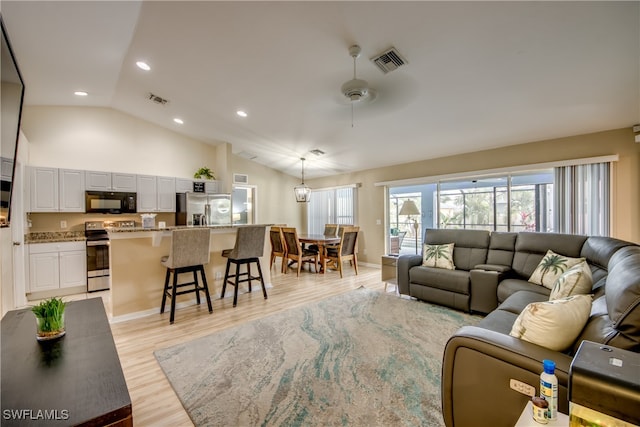 living room featuring ceiling fan, lofted ceiling, and light wood-type flooring