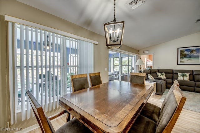 dining room with hardwood / wood-style flooring, a chandelier, and vaulted ceiling