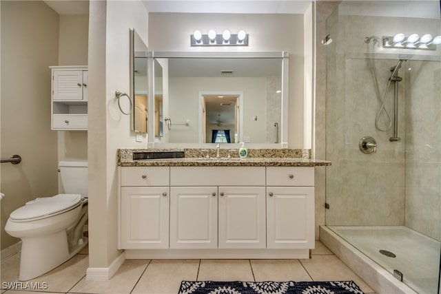 bathroom with tiled shower, vanity, tile patterned floors, and toilet