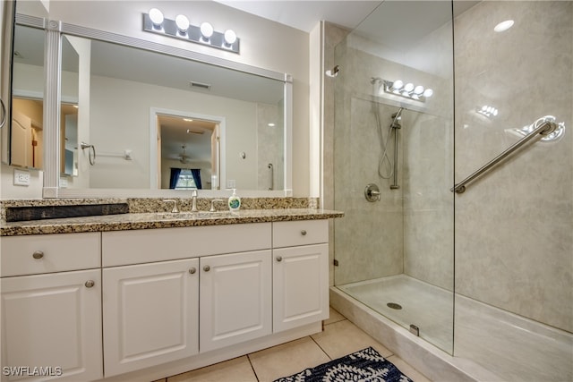 bathroom with tile patterned floors, vanity, and a tile shower