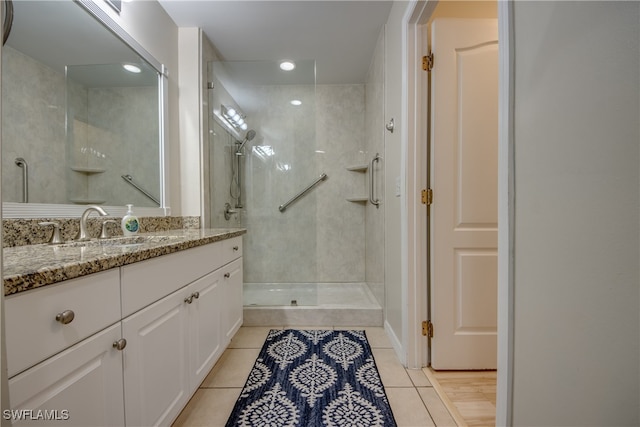 bathroom with tiled shower, vanity, and tile patterned floors