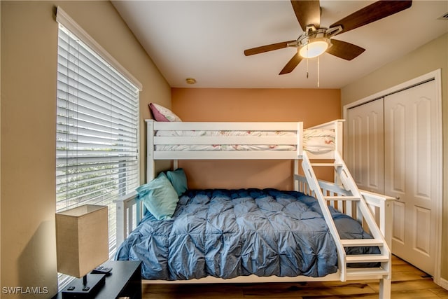 bedroom with a closet, light hardwood / wood-style floors, and ceiling fan