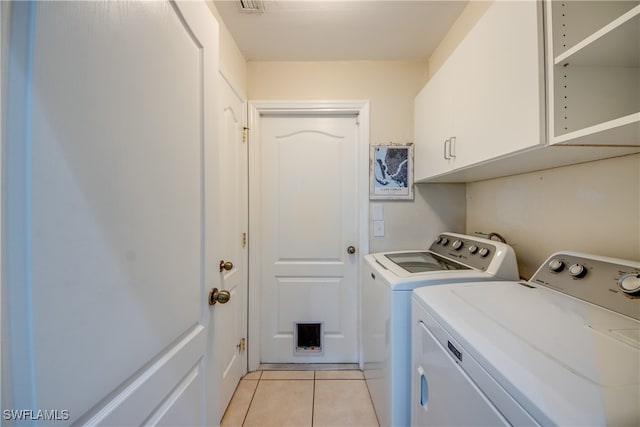 washroom featuring washer and dryer, cabinets, and light tile patterned floors