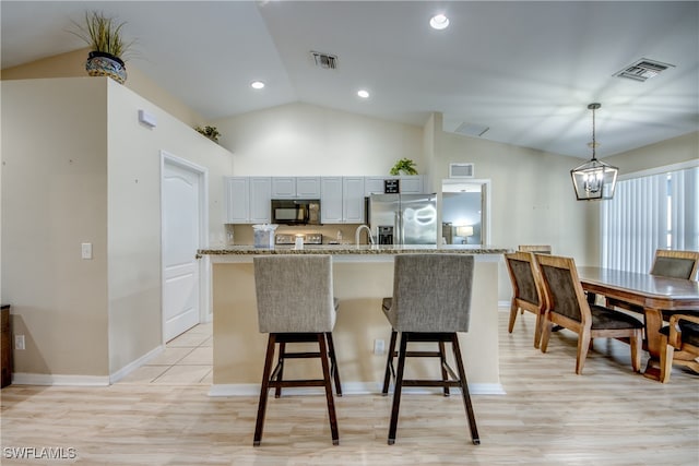 kitchen featuring vaulted ceiling, stainless steel fridge with ice dispenser, light hardwood / wood-style flooring, and decorative light fixtures