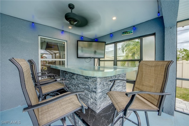 bar featuring ceiling fan, a healthy amount of sunlight, and stainless steel counters