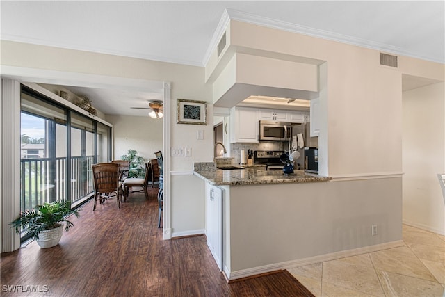 kitchen featuring white cabinets, light wood-type flooring, light stone counters, kitchen peninsula, and stainless steel appliances