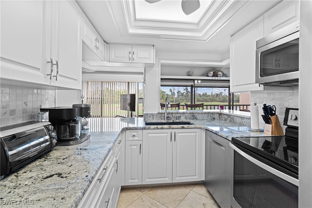 kitchen with white cabinets, appliances with stainless steel finishes, light stone counters, and sink