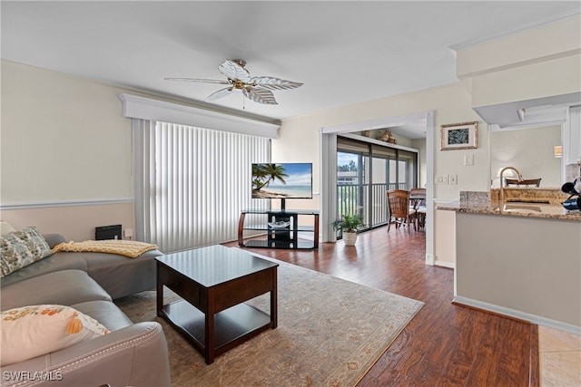 living room featuring ceiling fan, sink, and dark hardwood / wood-style floors