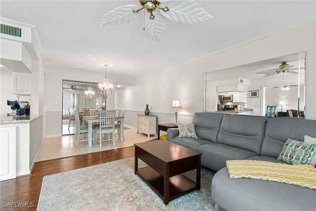 living room featuring crown molding, hardwood / wood-style floors, and ceiling fan with notable chandelier