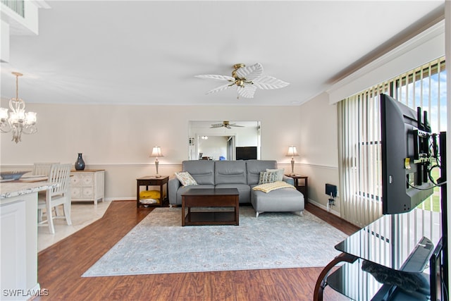 living room featuring crown molding, a healthy amount of sunlight, ceiling fan with notable chandelier, and wood-type flooring