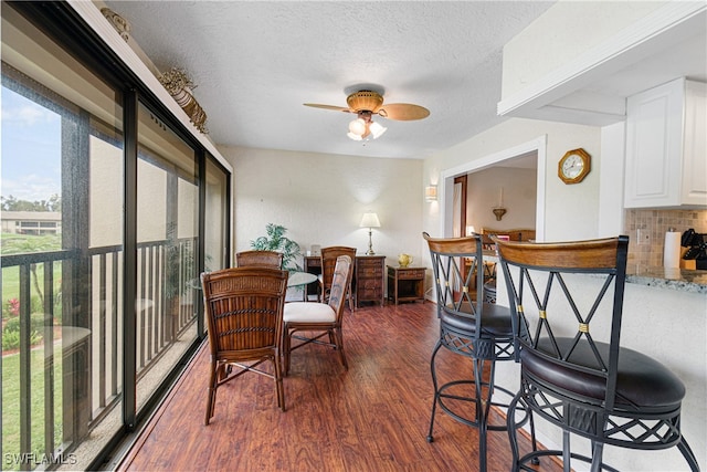 dining space featuring ceiling fan, dark wood-type flooring, and a textured ceiling