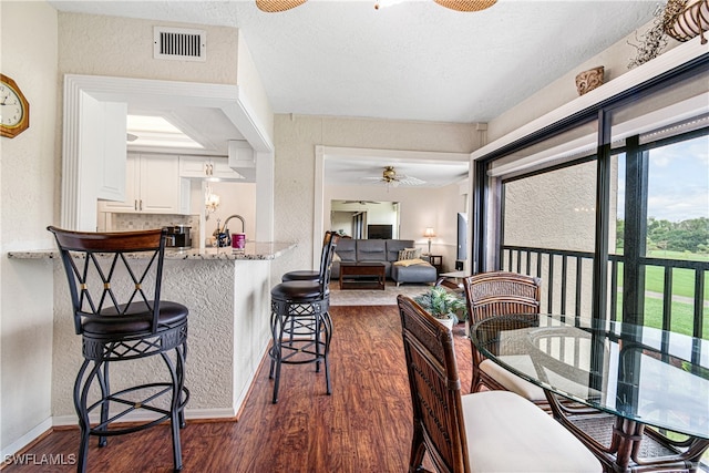 dining space featuring a textured ceiling, dark hardwood / wood-style flooring, and ceiling fan