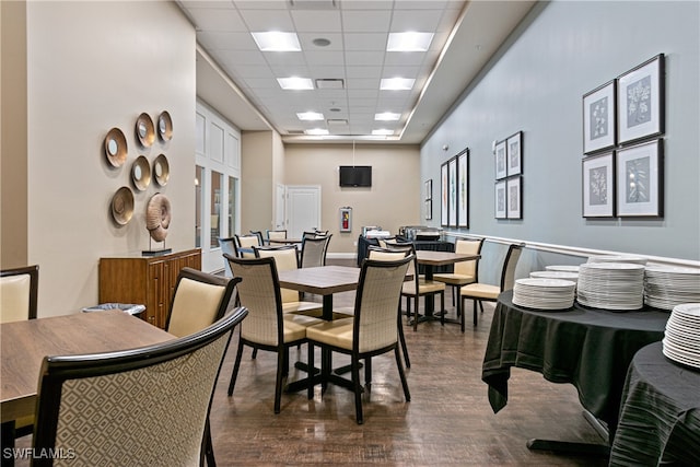 dining space with a drop ceiling and dark hardwood / wood-style flooring