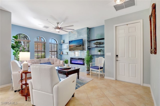 tiled living room featuring built in features, ceiling fan, and a tiled fireplace