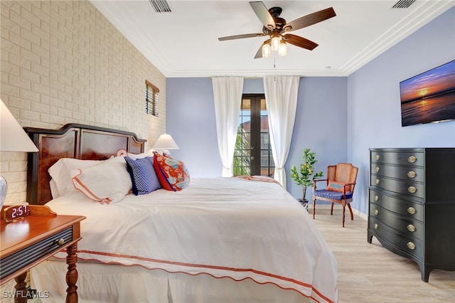 bedroom featuring light wood-type flooring, ceiling fan, ornamental molding, and brick wall