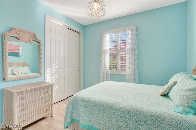 bedroom with an inviting chandelier, light hardwood / wood-style flooring, and a closet