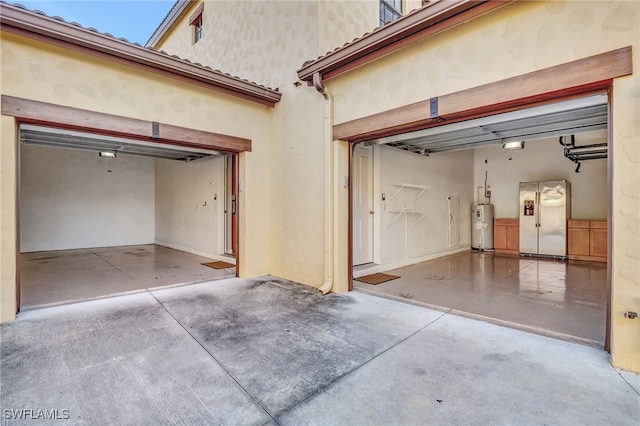 garage with stainless steel refrigerator with ice dispenser and water heater