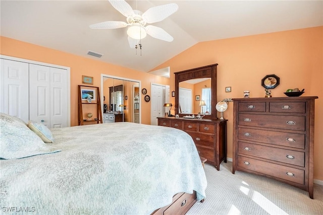 carpeted bedroom featuring ceiling fan, vaulted ceiling, and multiple closets