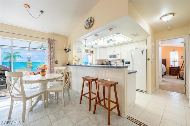 kitchen with decorative light fixtures, a breakfast bar, kitchen peninsula, white appliances, and white cabinetry