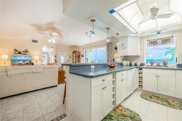 kitchen featuring hanging light fixtures, white cabinets, kitchen peninsula, and backsplash