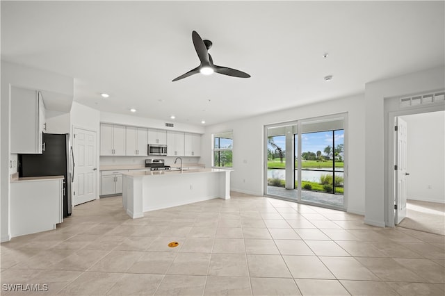 kitchen featuring white cabinetry, ceiling fan, a kitchen island with sink, light tile patterned floors, and appliances with stainless steel finishes