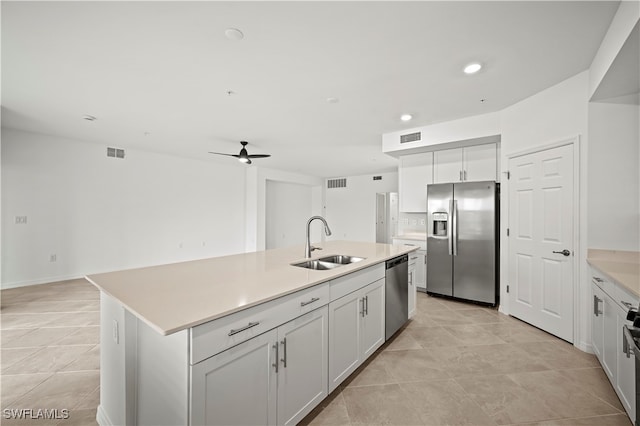 kitchen featuring stainless steel appliances, ceiling fan, sink, white cabinets, and an island with sink