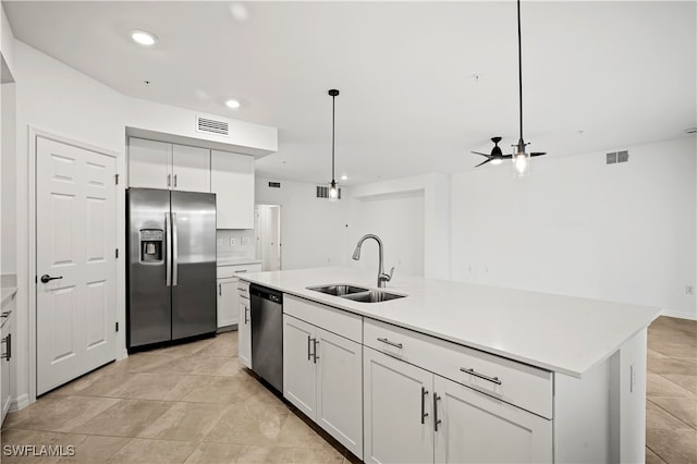 kitchen featuring stainless steel appliances, sink, white cabinetry, hanging light fixtures, and an island with sink