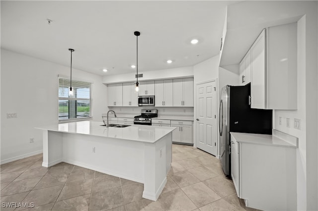 kitchen featuring stainless steel appliances, a kitchen island with sink, sink, white cabinets, and hanging light fixtures