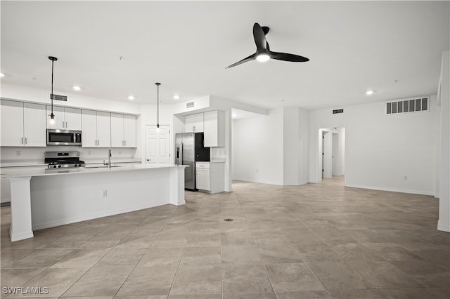 kitchen featuring a kitchen island with sink, white cabinetry, stainless steel appliances, and hanging light fixtures