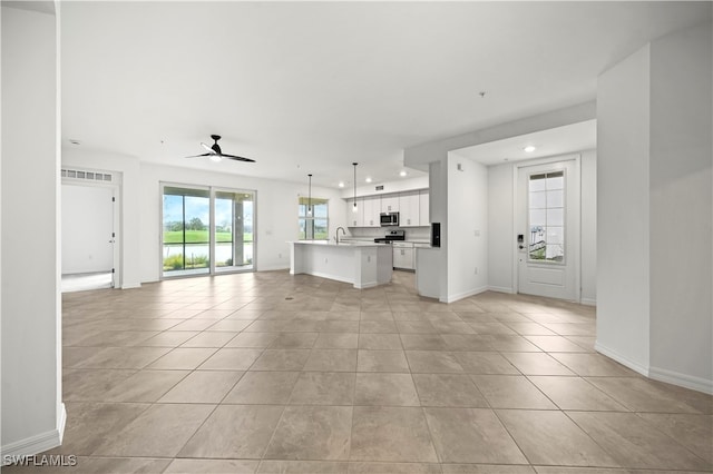 unfurnished living room with ceiling fan, light tile patterned floors, and sink