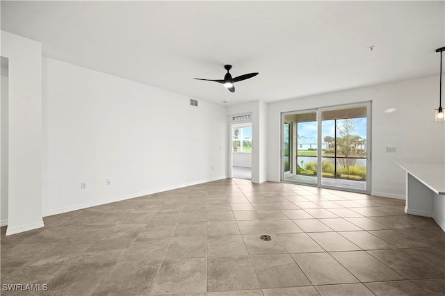 tiled empty room featuring ceiling fan and a healthy amount of sunlight