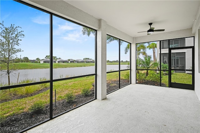 unfurnished sunroom featuring ceiling fan and a water view