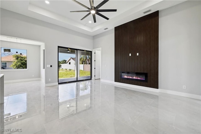 interior space featuring a fireplace, a raised ceiling, and ceiling fan