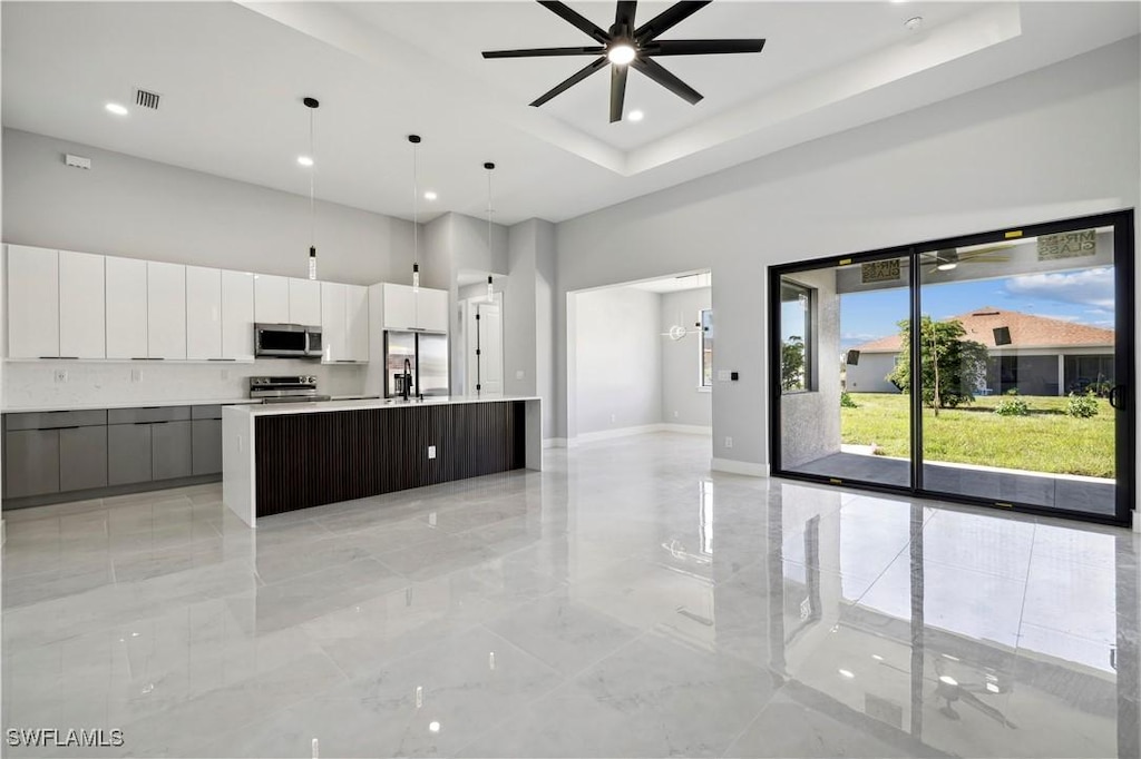 kitchen with dark brown cabinetry, ceiling fan, hanging light fixtures, a kitchen island with sink, and appliances with stainless steel finishes