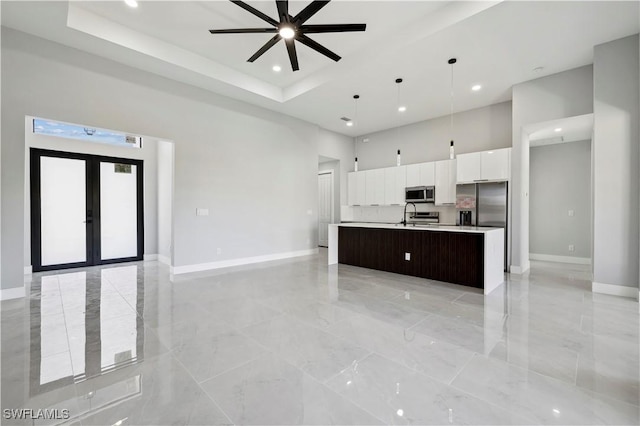 kitchen featuring appliances with stainless steel finishes, ceiling fan, sink, decorative light fixtures, and an island with sink